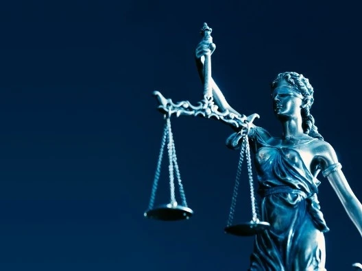 Estátua da Justiça segurando uma balança, em fundo azul